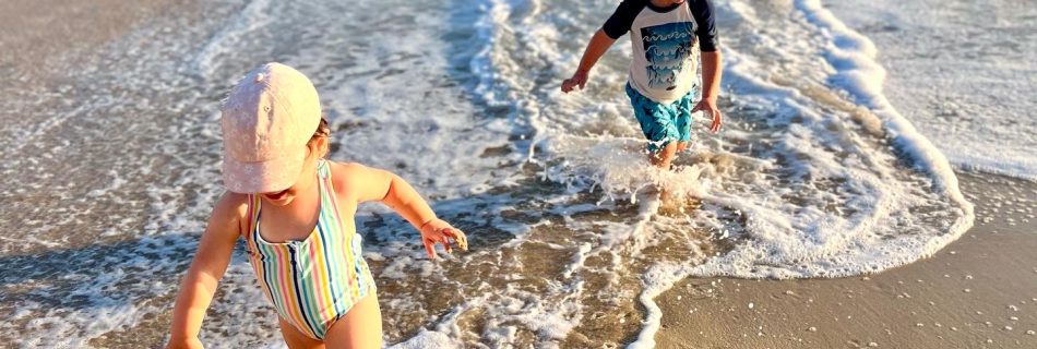 International travel with autistic kids – siblings running on a beach during family vacation.