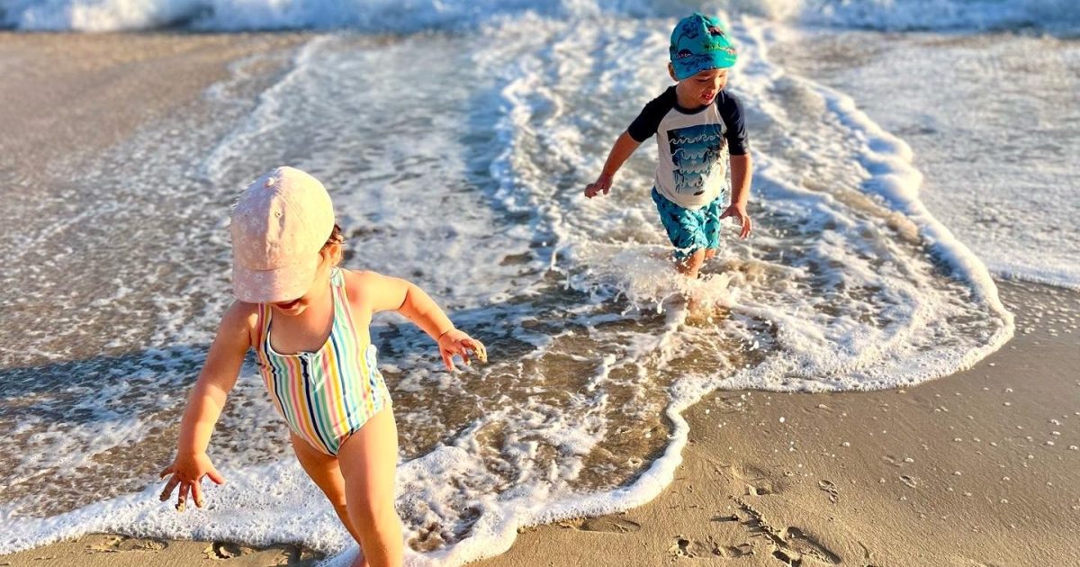 International travel with autistic kids – siblings running on a beach during family vacation.